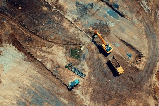 Aerial view of a construction site featuring heavy machinery and trucks, displaying industrial activity.